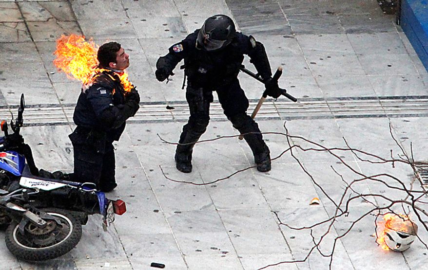 A motorcycle policeman burns as his colleague tries to help him after protesters threw a gasoline bomb in Athens on Wednesday, Feb. 23, 2011. Scores of youths hurled rocks and Molotov cocktails at riot police after clashes broke out during a mass rally that was part of a general strike. (AP Photo/Dimitri Messinis)