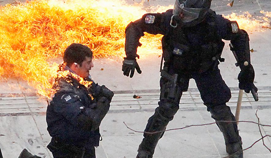 A motorcycle policeman burns as his colleague (right) tries to help him after protesters threw a gasoline bomb in Athens on Wednesday, Feb. 23, 2011. Scores of youths hurled rocks and Molotov cocktails at riot police after clashes broke out during a mass rally that was part of a general strike. (AP Photo/Dimitri Messinis)