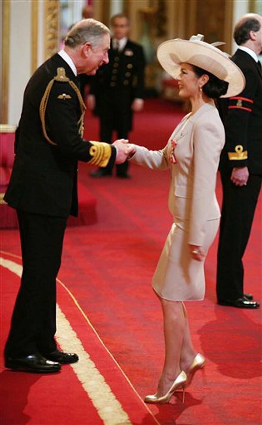 Hollywood actress Catherine Zeta Jones, right, is invested as a Commander of the British Empire (CBE) by Prince Charles at Buckingham Palace in London, Thursday Feb. 24, 2011. The Oscar-winning Welsh-born actress receives the royal honour for her services to the film industry and to charity. (AP Photo / Lewis Whyld, PA) UNITED KINGDOM OUT - NO SALES - NO ARCHIVES