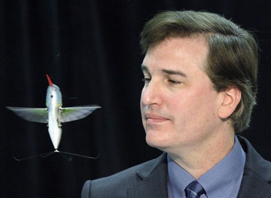 A tiny, drone aircraft designed to mimic a hummingbird, known as the "nano-hummingbird," is seen with a quarter for scale, during a briefing at the AeroVironment facility in Simi Valley, Calif., Friday, Feb. 25, 2011. With a 6.5-inch wing span, the remote-controlled hummingbird plane weighs less than an AA battery and can fly at speeds of up to 11 mph, propelled only by the flapping of its two wings. It can climb and descend vertically, fly sideways, forward and backward, as well as rotate clockwise and counterclockwise, and hover. (AP Photo/Reed Saxon)