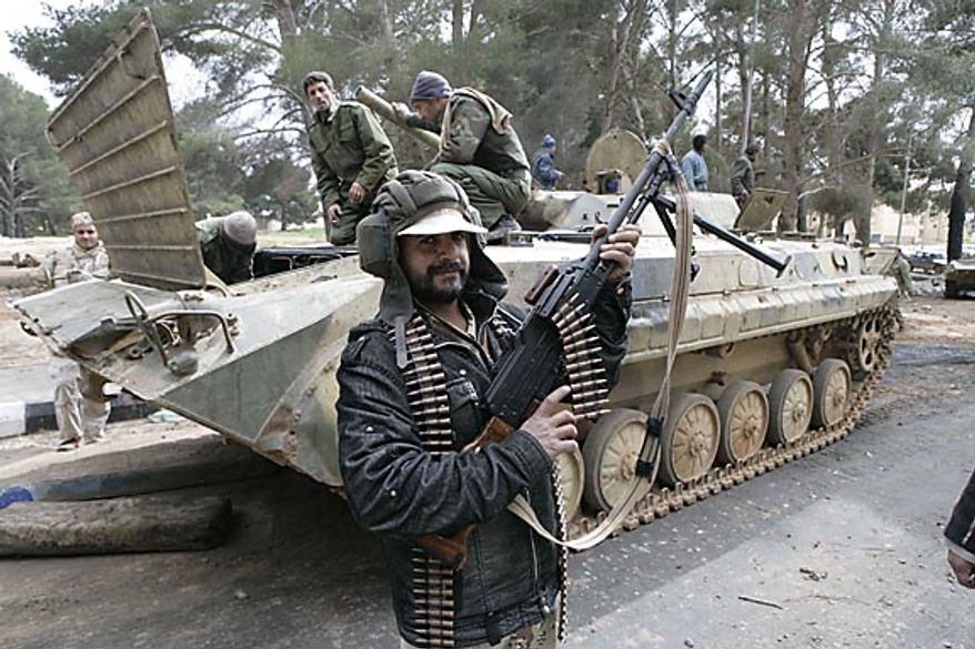 In this photo released by China's Xinhua News Agency, a man holding an automatic machine gun poses in front of a tank in the east Libyan city of Albayda Thursday, Feb. 24, 2011. (AP Photo/Xinhua, Nasser Nouri)