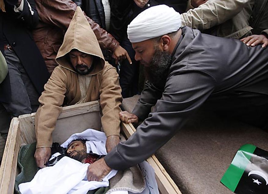 Clerics look at the dead body of a protester who was killed last week during protests against Libyan leader Moammar Ghadafi, in Benghazi, Libya, Friday Feb. 25, 2011. Militias loyal to Col. Gadhafi opened fire on protesters streaming out of mosques in the Libyan capital on Friday, demanding the regime's ouster, witnesses said, reporting at least four killed. Across rebellious cities in the east, tens of thousands held rallies in support of the first Tripoli protests in days. (AP Photo/Hussein Malla)