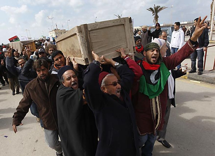 Mourners carry the coffins of two protesters who were killed last week during the demonstrations against Libyan leader Moammar Ghadafi in Benghazi, Libya, on Friday Feb. 25, 2011. Militias loyal to Col. Gadhafi opened fire on protesters streaming out of mosques in the Libyan capital on Friday, demanding the regime's ouster, witnesses said, reporting at least four killed. Across rebellious cities in the east, tens of thousands held rallies in support of the first Tripoli protests in days. (AP Photo/Hussein Malla)