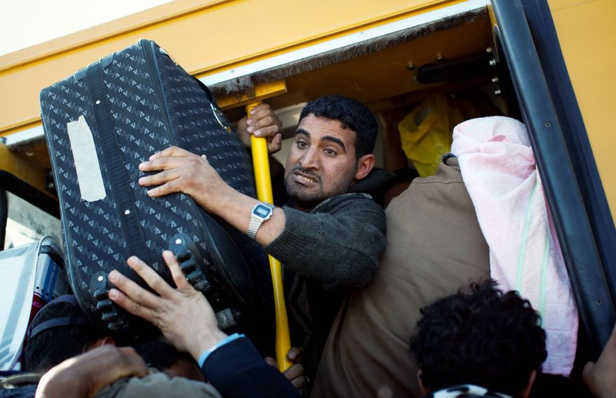 FLEEING FIGHTING: Egyptians who worked in Libya and are trying to get away from the emerging civil war there jam their belongings into a bus Thursday as they leave the country at the border near Ras Ajdir, Tunisia. (Associated Press)