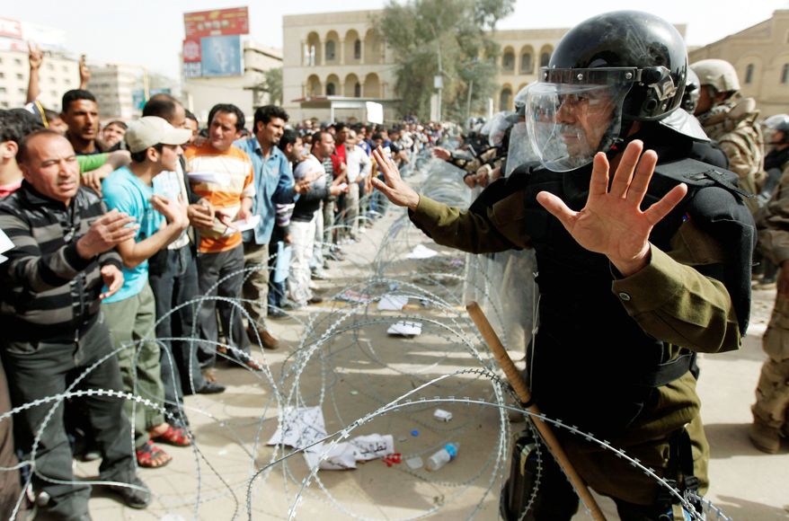Iraqi security forces close a bridge leading to the heavily guarded Green Zone while protesters chant anti-government slogans during a demonstration in Baghdad on Friday. Hundreds of people gathered in central Baghdad for an anti-government demonstration despite a vehicle ban that forced many to walk for hours to attend the rally. (Associated Press)