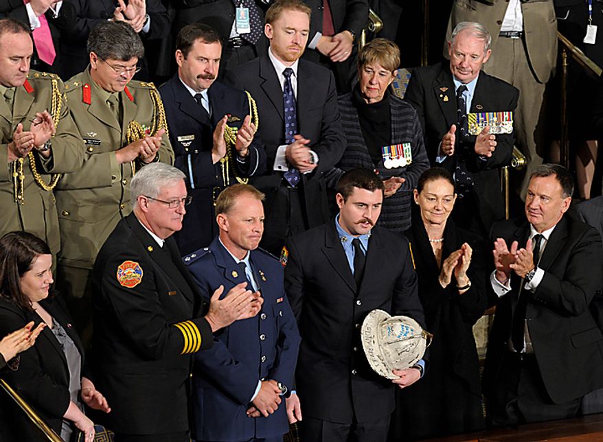 Australian firefighter Rob Frey, third from front left, and New York City firefighter James Dowdell, holding helmet, are recognized in a speech by Australian Prime Minister Julia Gillard, not pictured, during an address at a joint meeting of Congress on Capitol Hill in Washington, Wednesday, March 9, 2011. Mr. Frey participated in a joint exercise with New York City and Australian firefighters before the Sydney Olympics with Mr. Dowdell's father, Kevin Dowdell. Kevin Dowdell later died in the 9/11 attacks and Mr. Frey then returned the helmet to Mr. Dowdell's family. (AP Photo/Susan Walsh)