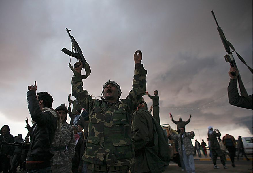 Libyan volunteers cheer as smoke rises from the oil port of Sidr in the background, in the eastern town of Ras Lanouf, Libya, Wednesday, March 9, 2011. A high-ranking member of the Libyan military flew to Cairo on Wednesday with a message for Egyptian army officials from Moammar Gadhafi, whose troops pounded opposition forces with artillery barrages and gunfire in at least two major cities. (AP Photo/Tara Todras-Whitehill)