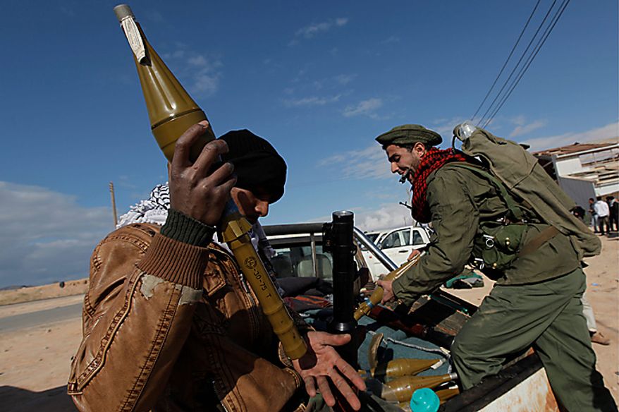 Two Libyan rebel fighters arm ammunition that was supplied to them in front of an ammunition storage wear house in the eastern town of Brega, Libya Wednesday, March 9, 2011. Moammar Gadhafi says Libyans will fight if a no-fly zone is imposed by Western nations, saying that would show their real intention is to seize the country's oil. (AP Photo/Nasser Nasser)