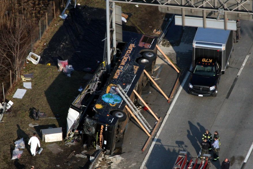 Emergency personnel respond to the bus crash on Interstate 95 in the Bronx borough of New York on Saturday, March 12, 2011, in which at least 14 people died. The bus, returning to New York from a casino in southeastern Connecticut, flipped onto its side and was sliced in half by the support pole for a large sign. (AP Photo/The Journal News, Frank Becerra Jr.)