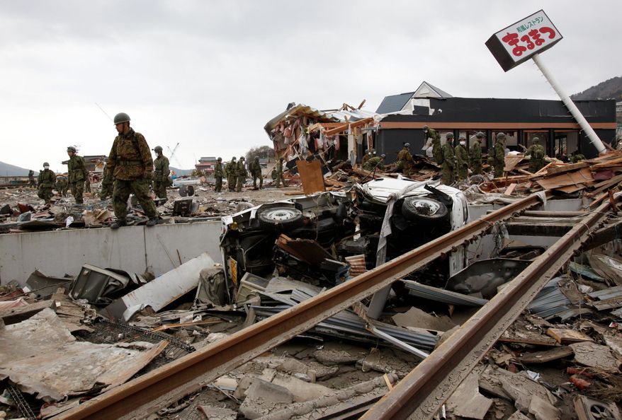 Japan Self-Defense Force members search for survivors of the earthquake and tsunami Tuesday in the devastated city of Ofunato, Japan. (Associated Press)