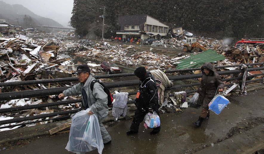 Residents of Kamaishi, Japan, walk away with personal items that they recovered from their damaged home in the aftermath of Friday&#x27;s tsunami. Two search-and-rescue teams from the United States and one from the United Kingdom with a total of about 220 personnel searched the town for survivors on Thursday, March 17, 2011. (AP Photo/Matt Dunham)