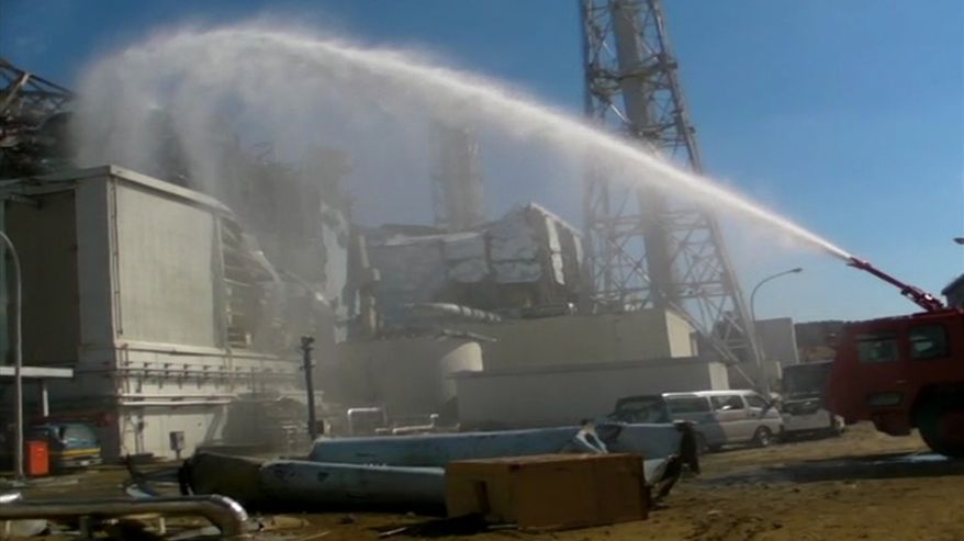 In this image taken from footage released by the Japan Defense Ministry, a fire engine from the Japan Self-Defense Forces sprays water toward Unit 3 of the troubled Fukushima Dai-ichi nuclear complex on Friday, March 18, 2011. (AP Photo/Japan Defense Ministry)