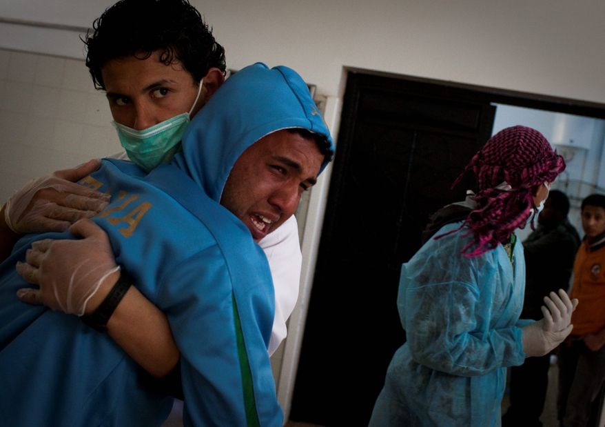 A Libyan is comforted Tuesday by a hospital staffer after identifying his brother in the morgue in Benghazi. The man's brother had been killed in fighting around the city of Ajdabiya. (Associated Press)