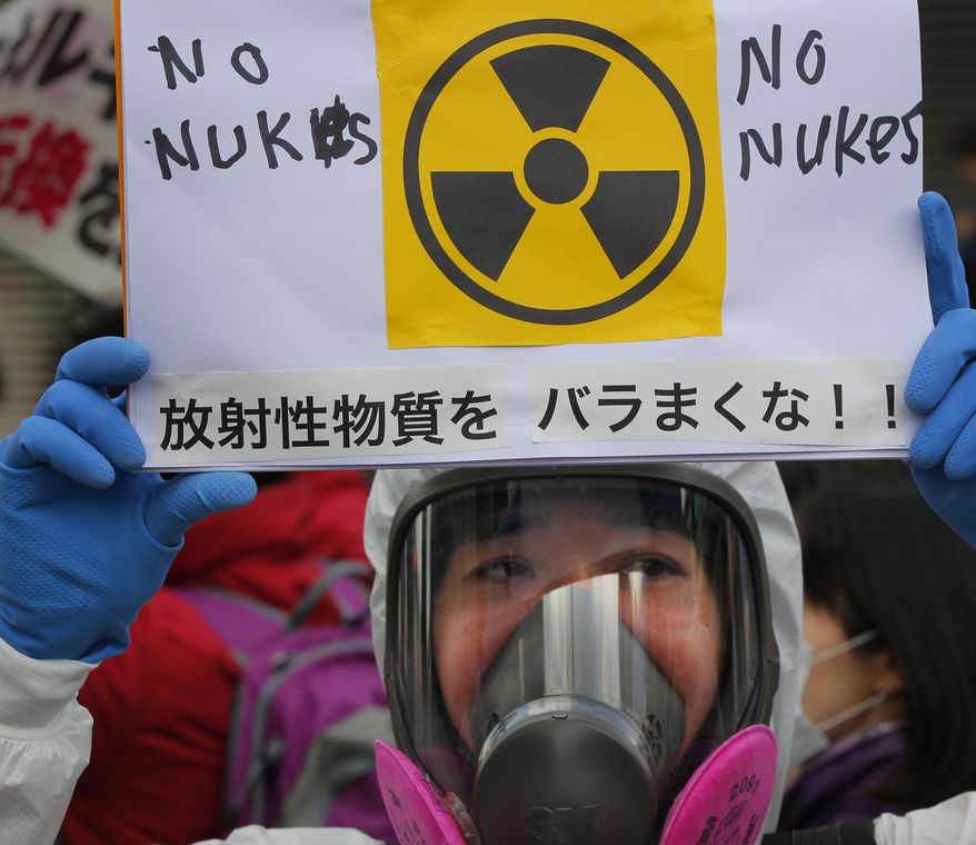A protester in protective mask holds a placard during an anti-nuclear rally in Tokyo on Sunday, March 27, 2011. The placard reads, "Don't spread radioactive substance." (AP Photo/Itsuo Inouye)