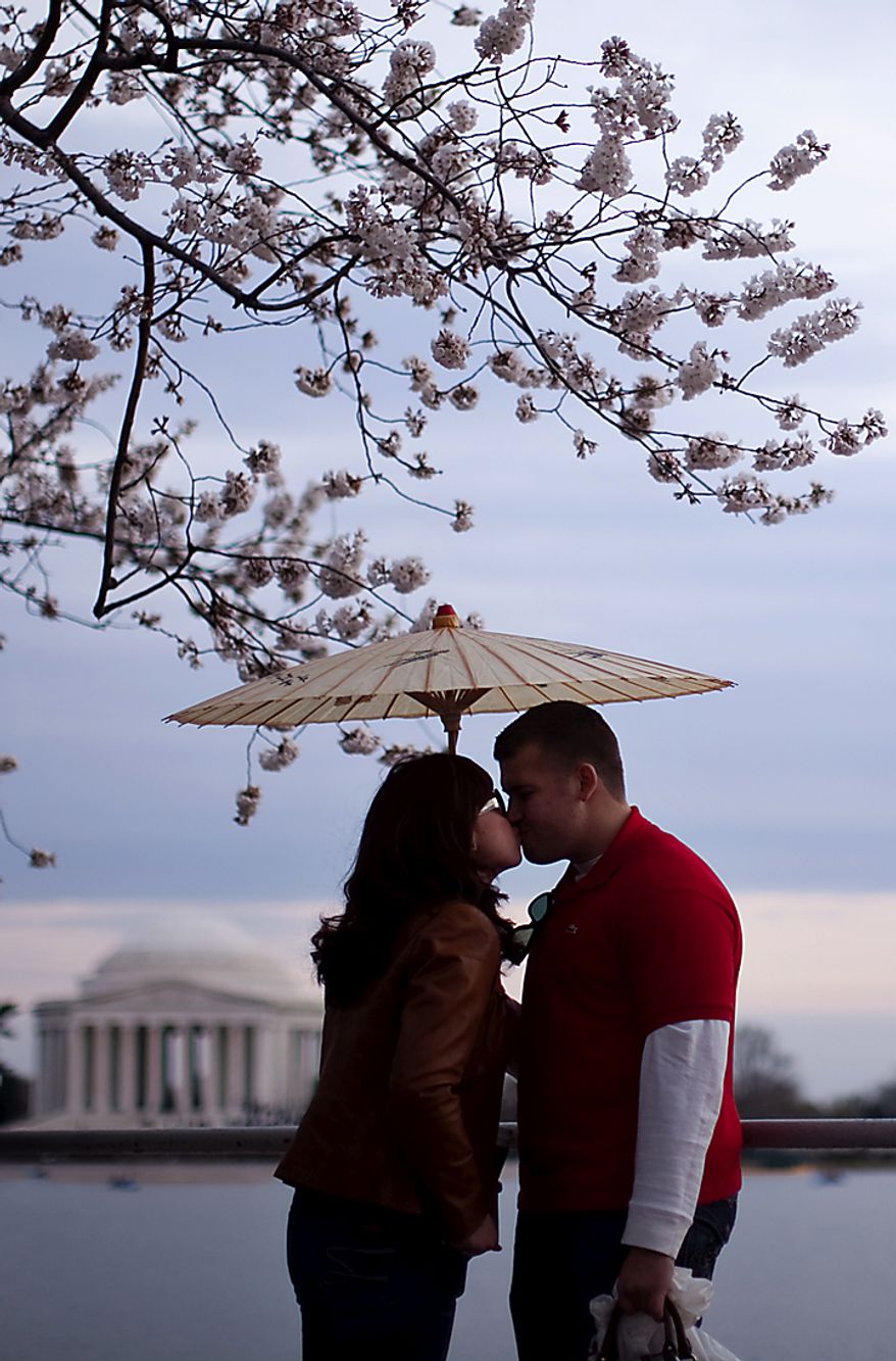 Kim Trang, left, and Kolin Fischer share a kiss under the cherry blossoms along the Tidal Basin, in Washington, D.C., Saturday, March 26, 2011. The couple are both from Arlington, Va. (Drew Angerer/The Washington Times)