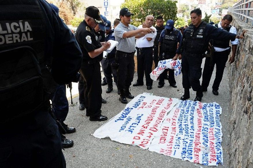 Police stand around a warning message painted on a banner left near the site where five dismembered bodies were found on the sidewalk next to a car in the Pacific resort city of Acapulco on Friday. Four of those killed were police officers who were abducted hours earlier. Acapulco is facing record levels of violence from warring drug cartels.