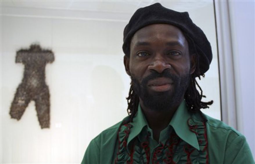 In this Tuesday, March 29, 2011 photo, Congolese artist Alfred Liyolo poses for a photo in front of one of his scuptures depicting a woman carrying a child at the opening of an art exhibition by 10 renowned Congolese artists in Johannesburg. The exhibition named "Art For Peace" will donate the proceeds to support women and child victims of sexual violence in eastern Congo. (AP Photo/Carley Petesch)