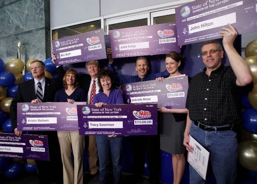 Mega Millions lottery winners — (from left) Leon Peck, Kristin Baldwin, Mike Barth, Tracy Sussman, John Kutey, Gabrielle Mahar and John Hilton — pose with $319 million checks during a news conference in Schenectady, N.Y., on Thursday. (Associated Press)