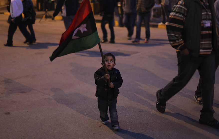 A Libyan child walks with a Libyan pre-Gadhafi flag during an evening demonstration in Benghazi, Libya, on Wednesday, March 30, 2011. Rebels retreated Wednesday from the key Libyan oil port of Ras Lanouf along the coastal road leading to the capital Tripoli after they came under heavy shelling from ground forces loyal to leader Moammar Gadhafi. (AP Photo/Altaf Qadri)