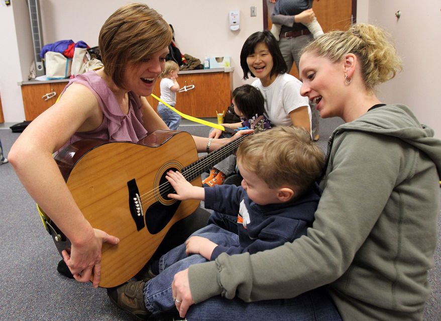 This Monday, March 7, 2011, photo shows Joni Pappas left, as she plays guitar with Jackson Brooks, 2, and his mother, Lauren Brooks, both of Huntington, during Pappas toddler music class at Marshall University in Huntington, W.Va. (AP Photo/The Herald Dispatch, Lori Wolf)
