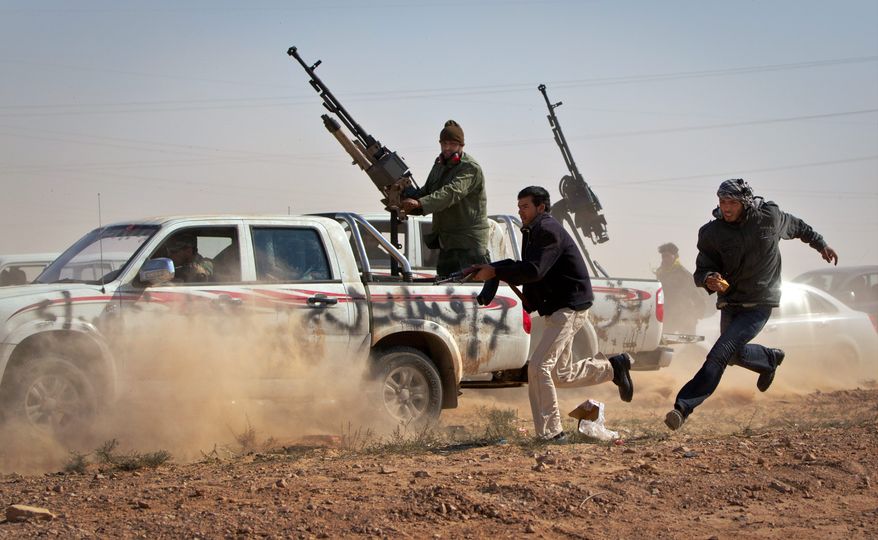 Rebel fighters chase a vehicle belonging to Col. Moammar Gadhafi's forces in a bid to shoot out its tires as it sped through the front line east of Brega on Sunday. The vehicle was driven by a boy who said he had spent two days in besieged Brega and stole the vehicle in order to return to the rebel side. (Associated Press)