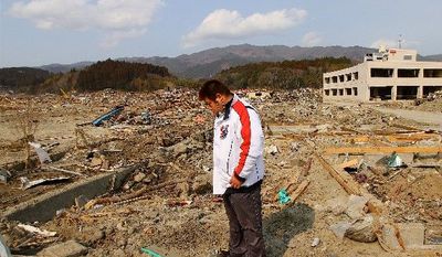 Naoki Suzuki, a truck driver, stands near the site of his home in downtown Rikuzen-Takata where his wife, Kazue, tried to ride out the tsunami as it rose above a nearby three-story apartment complex and post office. (Christopher Johnson/Special to The Washington Times)