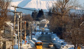 With Mount Katahdin rising in the background, a school bus makes its rounds in Millinocket, Maine, in 2011. The town&#39;s public high school is touting its natural resources in an effort to offset a dwindling population by recruiting foreign students. (Associated Press)