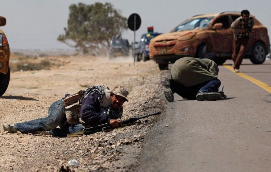 UNDER FIRE: Two Libyan rebels duck as others take cover when attacked by pro-Gadhafi forces along the front line on the outskirts of Brega, Libya, on Monday. Meanwhile, a government envoy is in Europe for talks about ending the fighting. (Associated Press)