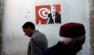 Tunisian men pass a poster with the face of former Tunisian President Zine El Abidine Ben Ali torn away in downtown Sfax, Tunisia. Tunisians have embarked on a difficult transition to democracy since overthrowing their autocratic ruler of 23 years nearly three months ago. They cherish their new freedom, but also worry about the future. (Associated Press)