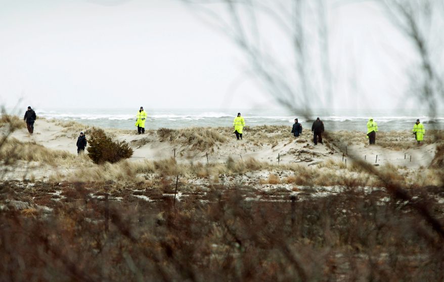Emergency personnel search the dunes and scrub near Oak Beach, N.Y., across the road from where eight bodies have been found. (Associated Press)