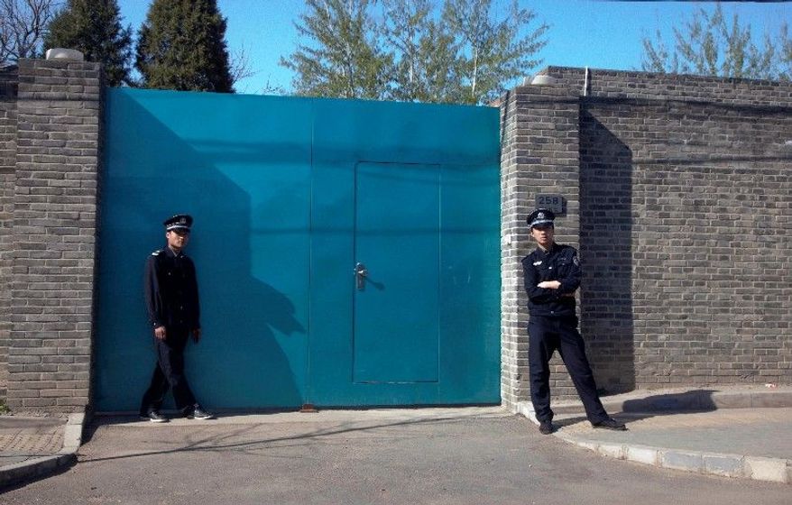 A Chinese police officer (right) and a security guard stand outside the entrance to Ai Weiwei's studio in Beijing. (Associated Press)