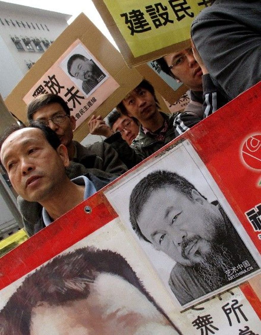Human rights protesters carry placards with a picture of Ai Weiwei and the phrase "Release Ai Weiwei" outside the China Liaison Office in Hong Kong during a protest on Tuesday. Chinese police have called more people in for questioning as they expand their investigation of the avant-garde artist, who has not been heard from since being taken into custody over the weekend, friends said. (Associated Press)