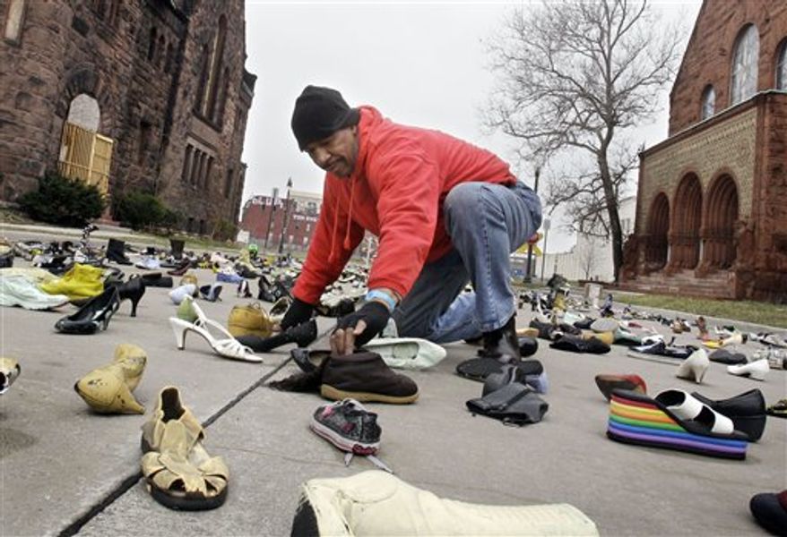 Artist Tyree Guyton adjusts shoes at his "Street Folk" installation on Edmund Place in Detroit, Thursday, April 7, 2011. Guyton says "the shoes are a reflection of people, all going in different directions and yet they are all in the streets." (AP Photo/Carlos Osorio)