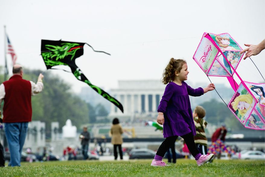 Claire Tarallo, 5, of Herndon, tries to get her Disney kite aloft Sunday at the annual kite festival on the Mall. (Drew Angerer/The Washington Times)