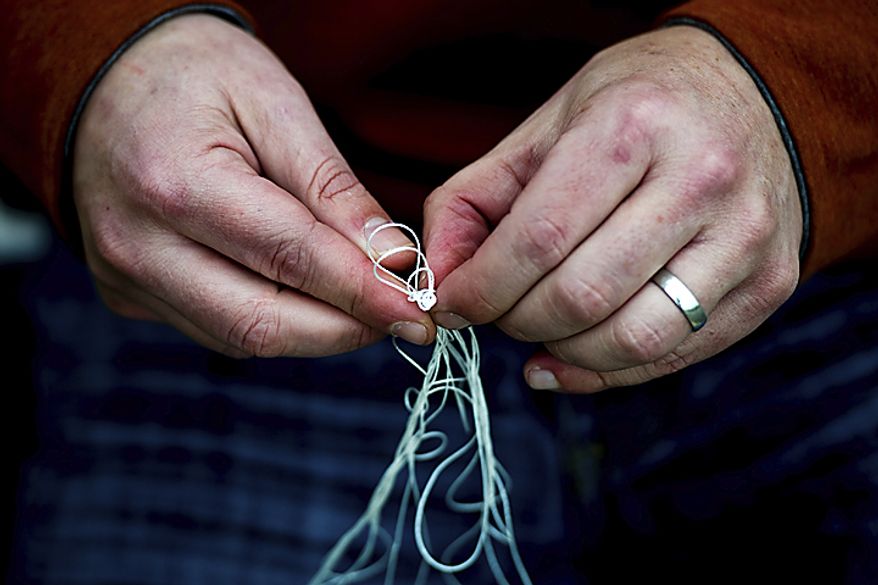 Richard Almon, of Seven Corners, Va., tries to undo a knot in his kite during the annual Kite Festival on the National Mall, in Washington, Sunday, April 10, 2011. "I borrowed it from a friend, so I really need to fix this thing and get it back to her in one piece," he said. (Drew Angerer/The Washington Times)