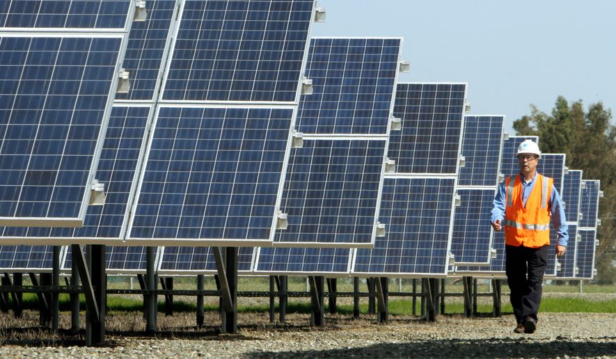 Greg Bosscawen, manager of renewable energy for Pacific Gas and Electric Co., walks past solar panels at PG&amp;E&#39;s Vaca-Dixon solar energy site near Vacaville, Calif., on Tuesday. Gov. Jerry Brown signed legislation Tuesday that would require California utilities to get one-third of their power from renewable sources. (Associated Press)