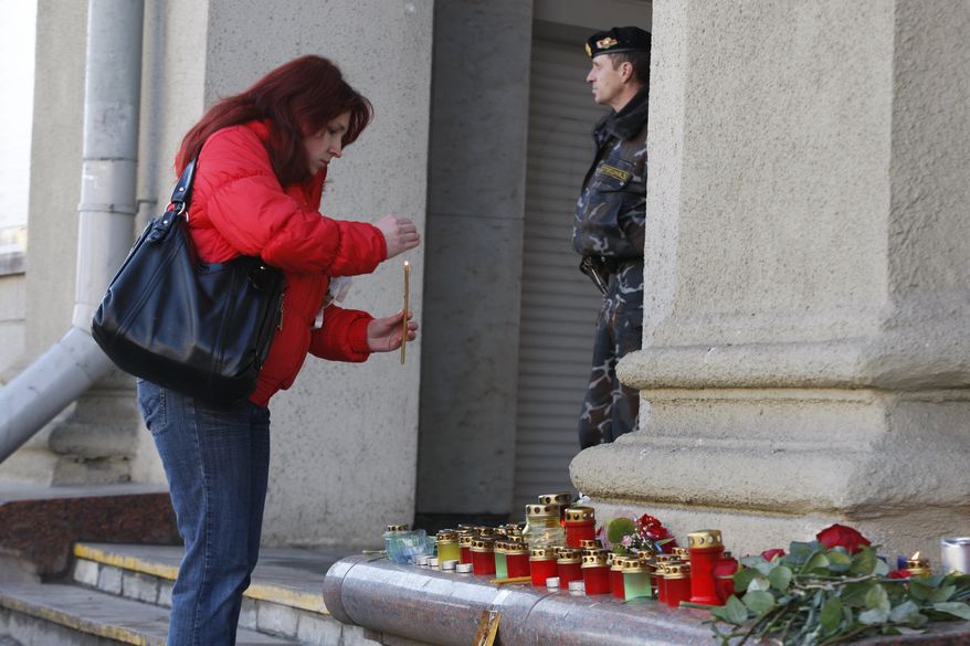 A woman lights a candle at an entrance to the Oktyabrskaya station of Minsk subway in downtown on Tuesday, April 12, 2011. Belarusian authorities said Tuesday they have identified a suspect in a subway bombing as the death toll rose to 12, with more than 200 wounded. (AP Photo/Sergei Grits)