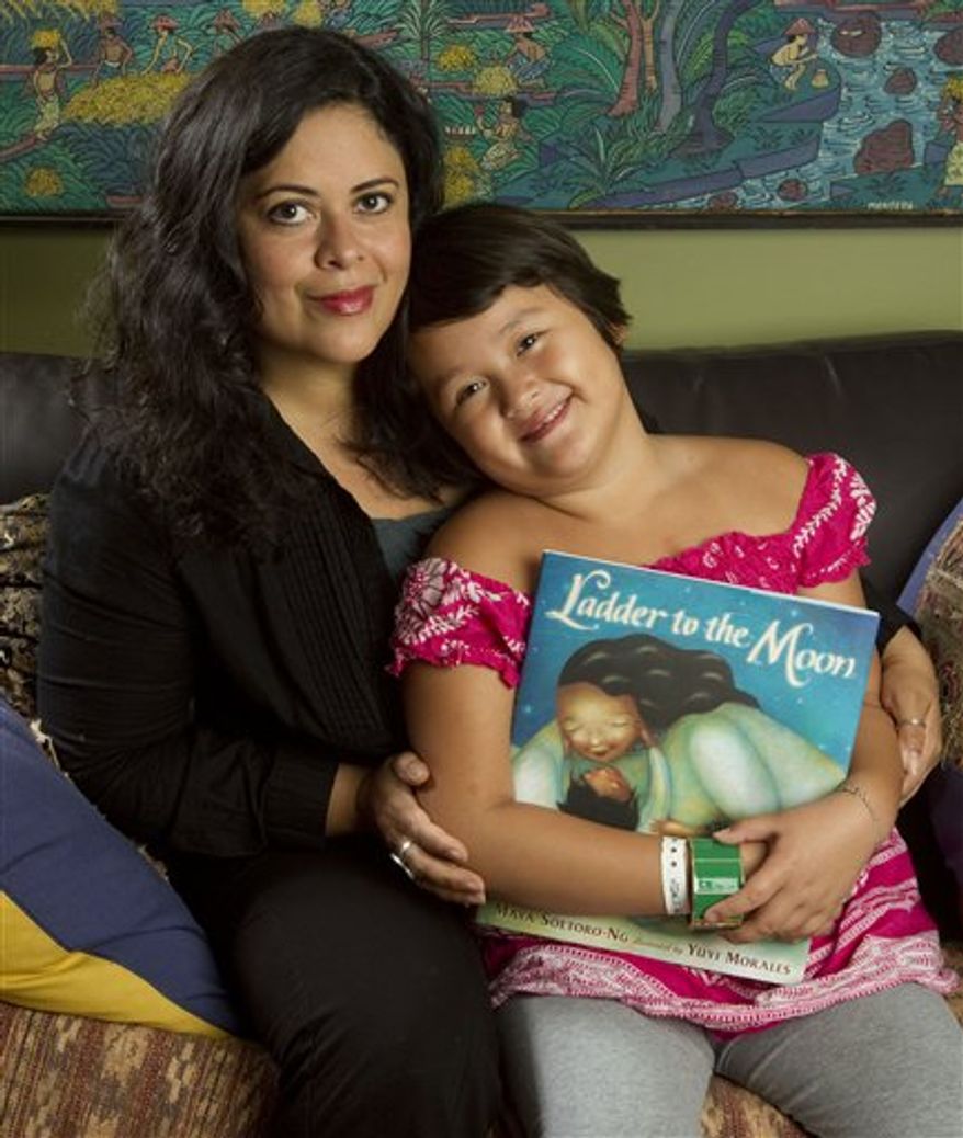 This Tuesday, March 29, 2011 photo shows Maya Soetoro-Ng, left, and her daughter Suhaila Ng, 6, as they look at Soetoro-Ng's new book, "Ladder to the Moon," at their home in Honolulu. Soetoro-Ng, President Obama's sister, draws on memories of their mother, Ann Dunham, for her new picture book. (AP Photo/Eugene Tanner)