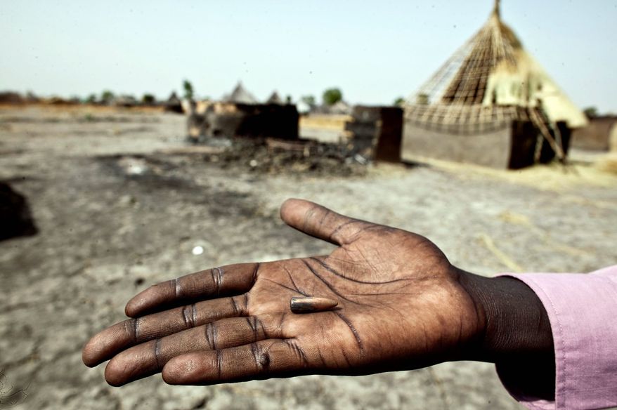A survivor of a massacre by rebel forces displays a bullet in front of burned houses in Fangak, Southern Sudan. The attack by rebel leader George Athor was carried out in February. Officials said 241 people died, most of them civilians. The rebel leader, a former high-ranking officer in the southern army, launched an insurrection after losing his bid for governor of Jonglei state last April. (Associated Press)