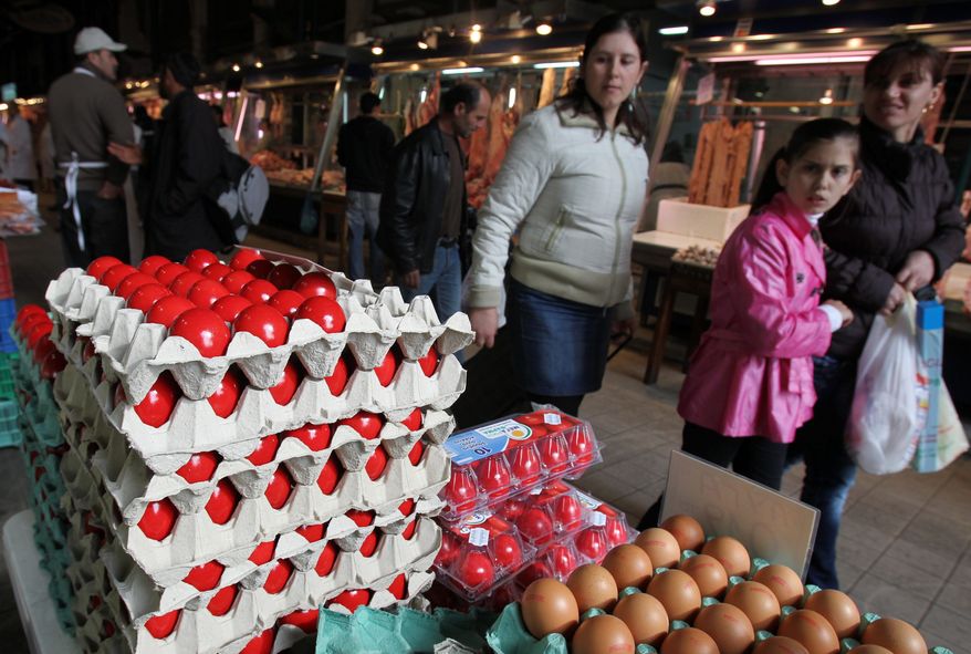 A woman and her children examine eggs died red under an old Greek Easter tradition in a central market of Athens on Wednesday. Nearly a year after Greece was rescued from bankruptcy by an international bailout, the country's businesses are reeling from stringent austerity measures imposed as a means to pull the economy out of its debt hole. As Greeks see their disposable income shrink, the National Confederation of Hellenic Commerce says 65,000 small and medium-sized enterprises shut down last year. (Associated Press)