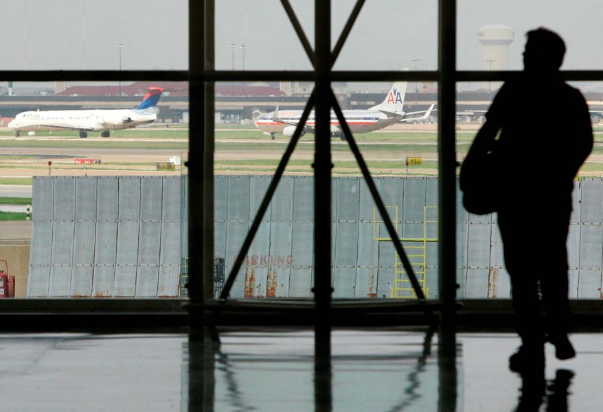 ** FILE ** A traveler waits in Terminal C at Dallas-Fort Worth International Airport in 2008 as passenger jets taxi nearby. (Associated Press)