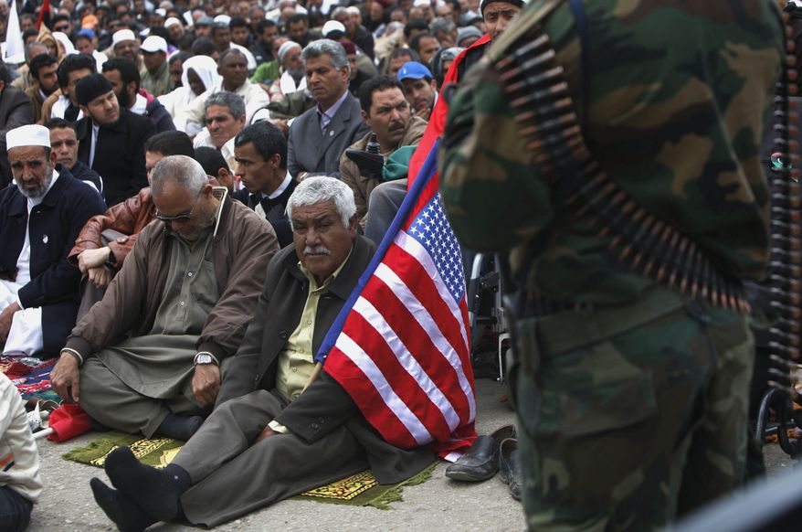 A Libyan man carries a U.S. flag while attending Muslim weekly Friday prayers in Benghazi, Libya, Friday, April 22, 2011. U.S. Sen. John McCain praised Libya's rebels as his "heroes" in a visit to their de facto capital Friday, a day after the United States started flying armed drones to bolster NATO firepower and try to break a battlefield stalemate with Moammar Gadhafi's forces. (AP Photo/Nasser Nasser)