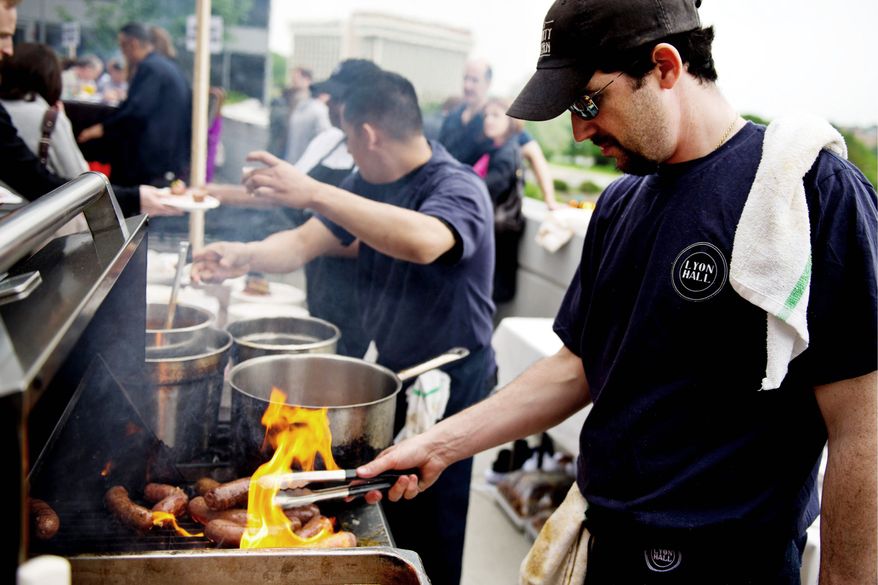 PHOTOGRAPHS BY DREW ANGERER/THE WASHNGTON TIMES
Liam LaCivita, executive chief of Lyon Hall restaurant in Arlington, grills half-smokes on the rooftop terrace of Domaso Restaurant during the Top Dog Half-Smoke Challenge on Sunday. He braised short ribs and used a mustard made with beer from a local brewer for his half-smokes.