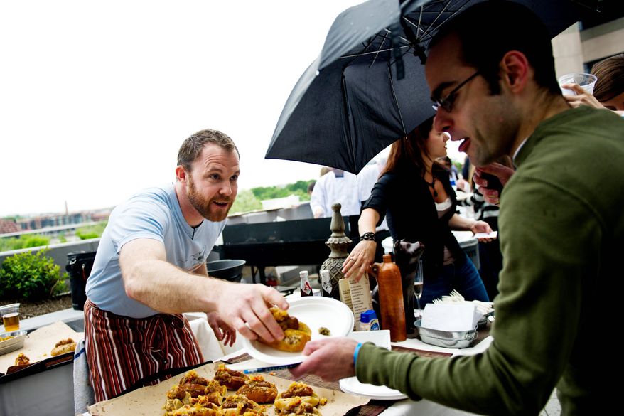 DREW ANGERER/THE WASHINGTON TIMES
Dennis Marron, head chef at Jackson 20 Restaurant, serves a hickory-smoked half-smoke to a patron on the rooftop terrace of Domaso Restaurant. The winning entry in the friendly competition was Firefly restaurant on Dupont Circle with its fennel sausage and half-smoke bacon chili entry.