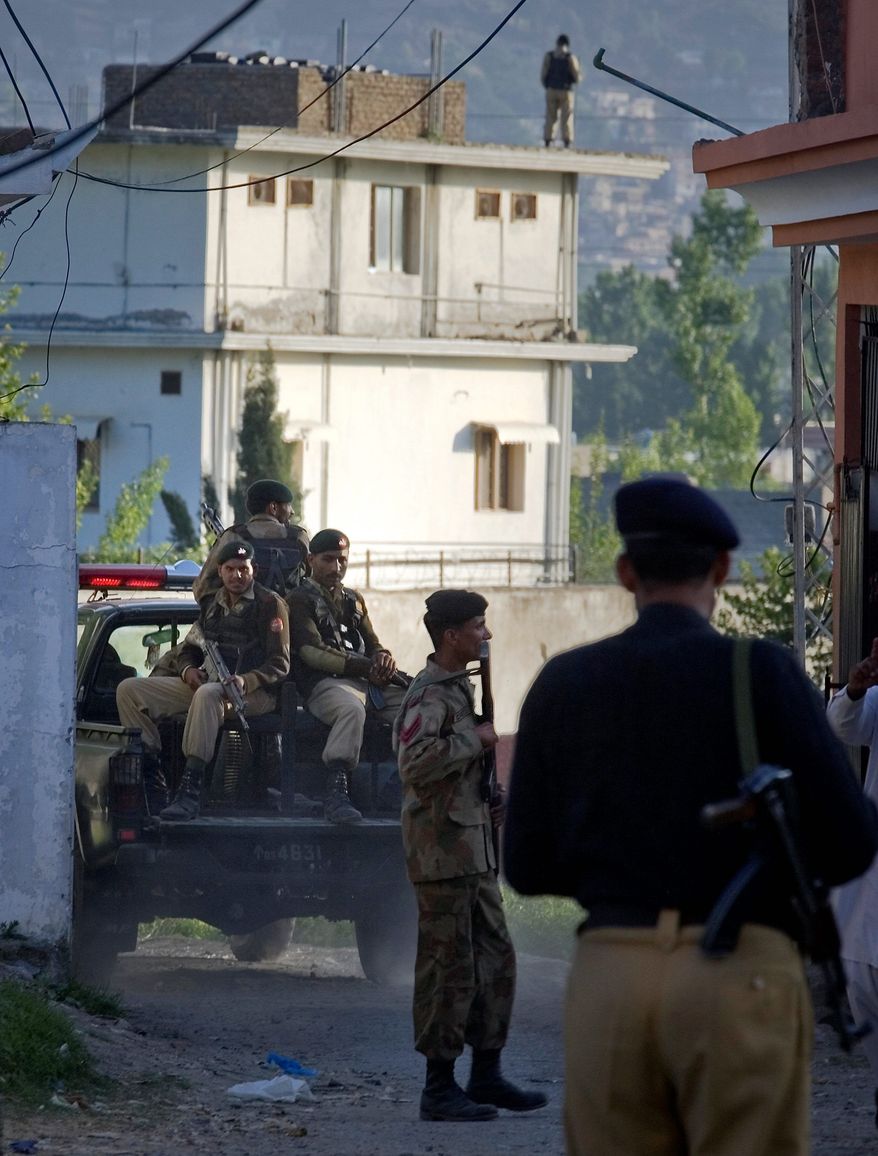 Pakistan army soldiers and a police officer patrol past the house (background) where al Qaeda leader Osama bin Laden was killed by U.S. forces on Sunday, ending a nearly 10-manhunt after the Sept. 11 attacks on U.S. soil. (Associated Press)