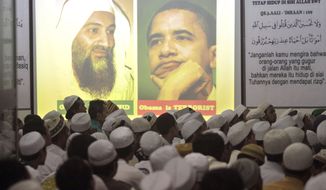 PRAYERS: Members of the hard-line group Islam Defenders Front gather by portraits of Osama bin Laden and President Obama in Jakarta, Indonesia, during prayers Wednesday for the al Qaeda leader killed by U.S. forces in Pakistan. Mr. Obama is scheduled to meet Thursday with Sept. 11 families in New York. (Associated Press)