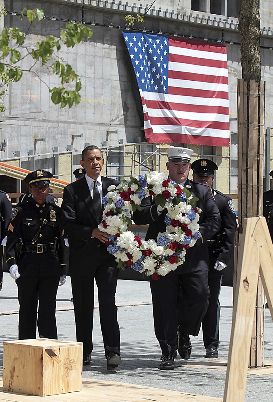 President Barack Obama, accompanied by a New York City Police officer, New York City Firefighter, and Port Authority officers, carries a wreath to be placed at the World Trade Center site, in New York, Thursday, May 5, 2011. (AP Photo/Richard Drew)