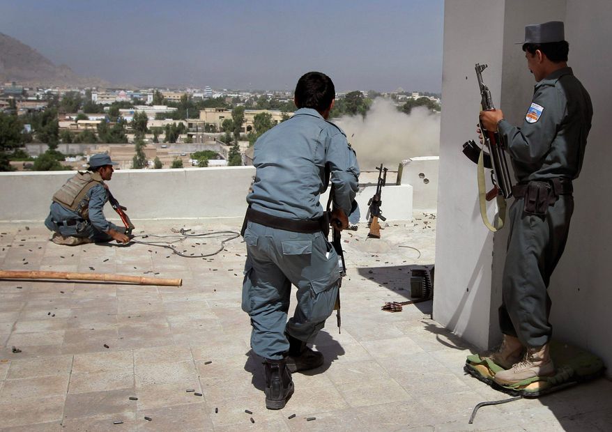 ASSOCIATED PRESS
An Afghan policeman runs to take up a position Sunday on a rooftop against Taliban fighters hiding in a government building from which smoke is rising in Kandahar on the second day of a major assault.