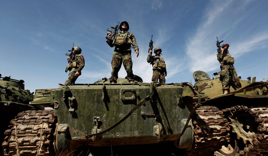 Afghan soldiers stand guard on hulks of tanks destroyed during the Soviet occupation as part of a training session at Camp Morehead near Kabul. (Associated Press)