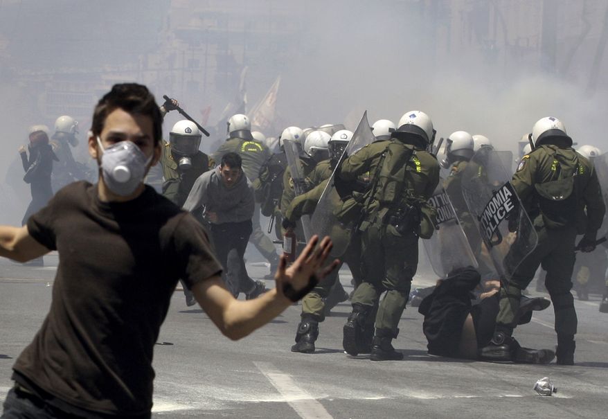 A young protester runs as others are hit by riot police during clashes Wednesday in Athens. Riot police made heavy use of tear gas and stun grenades to disperse youths throwing stones and petrol bombs during a march attended by 20,000 people to protest the Greek government's harsh austerity measures. (Associated Press)